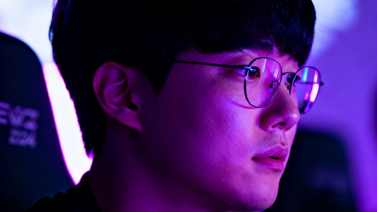 Faker李相赫在2024赛季EWC英雄联盟决赛舞台上专注操作的侧影，霓虹紫色灯光映照在他面部，展现出传奇中单的沉稳气场。